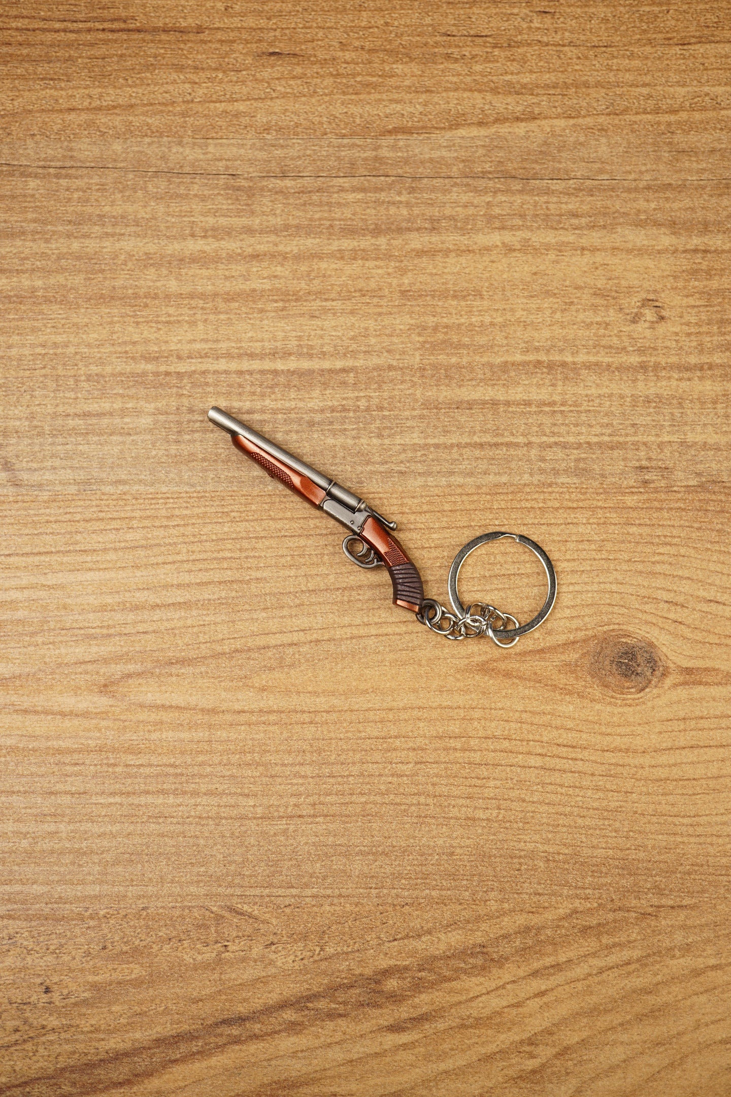 12 gauge shotgun keyring on wooden background with visible twin-barrel design, compact gamer accessory and collectible keychain loop
