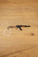 AK-74 rifle keyring laid flat on wooden surface with metal key loop, ideal tactical FPS gamer gift and collectible bag charm