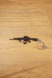 AK-12 rifle keyring with drum magazine on a wooden surface, showing the full metal gamer collectible with chain and ring attached
