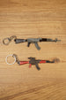 AKM 7.62x39 rifle keychain replicas in base and red modded styles laid flat on a wooden surface for tactical gamer collectors
