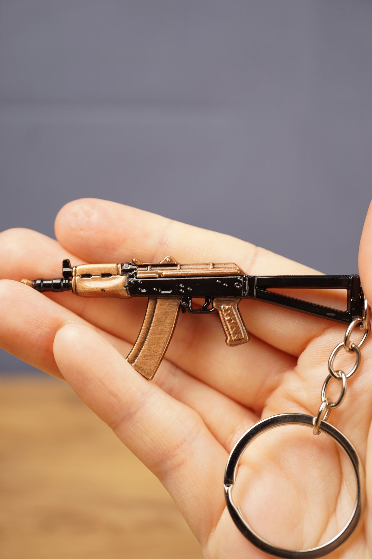 AKS-74U rifle keyring held in hand for scale, showing the compact metal gamer keychain with silver ring and detailed tactical styling