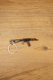 AKS-74U rifle keyring laid flat on a wooden surface, showing the compact metal gamer keychain with bronze and black tactical detailing