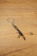 AKS-74U metal rifle keychain displayed vertically on a wooden background, ideal as a tactical gaming gift or backpack charm