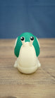Front view of the Palia Garden Snail Plush collectible figure with a cream-colored body, bright green shell and two expressive black and white eyes