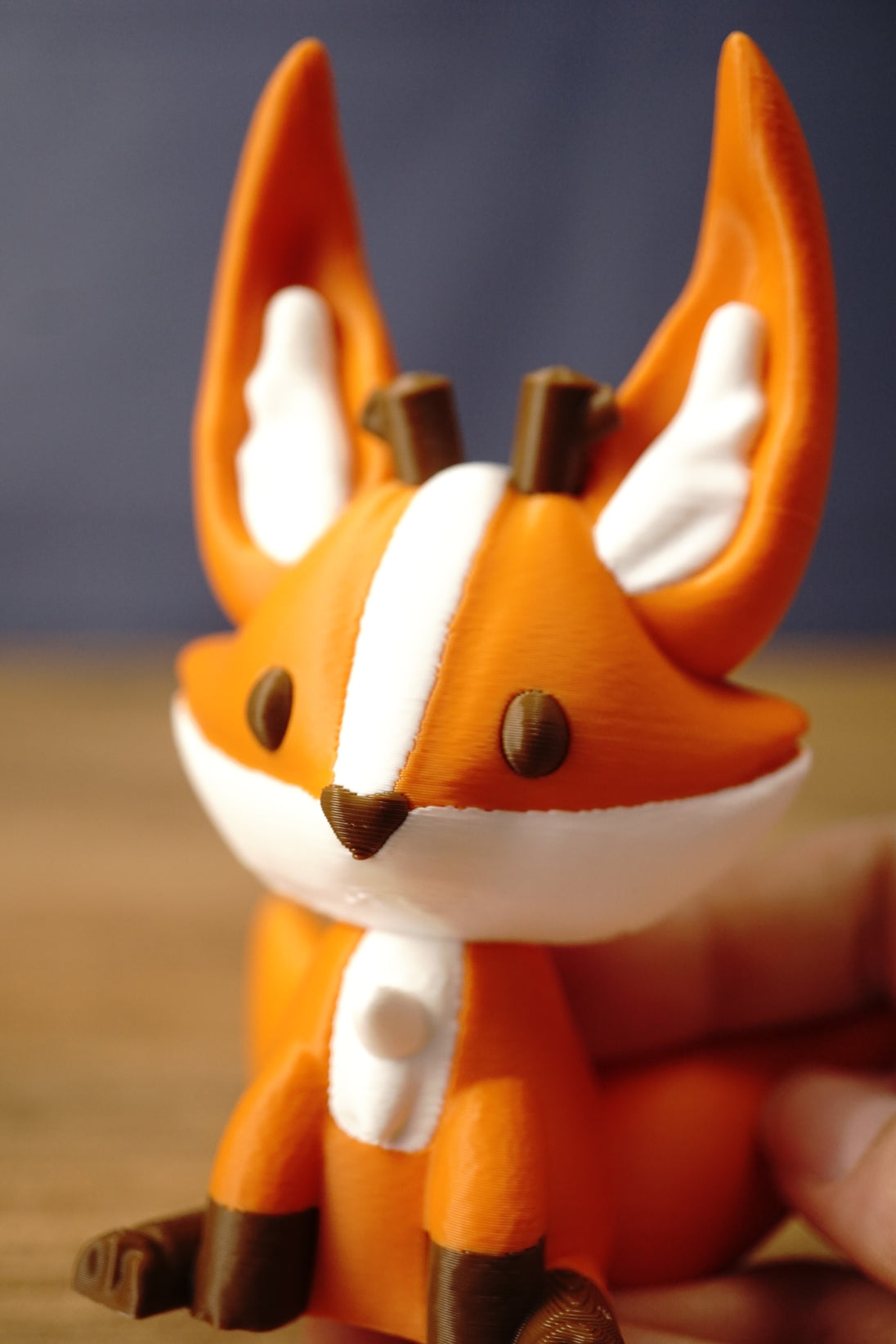 Close-up of an Ancient Kitsuu-inspired fox figure’s face, featuring tall orange ears, white markings, brown antlers, and dark eyes.