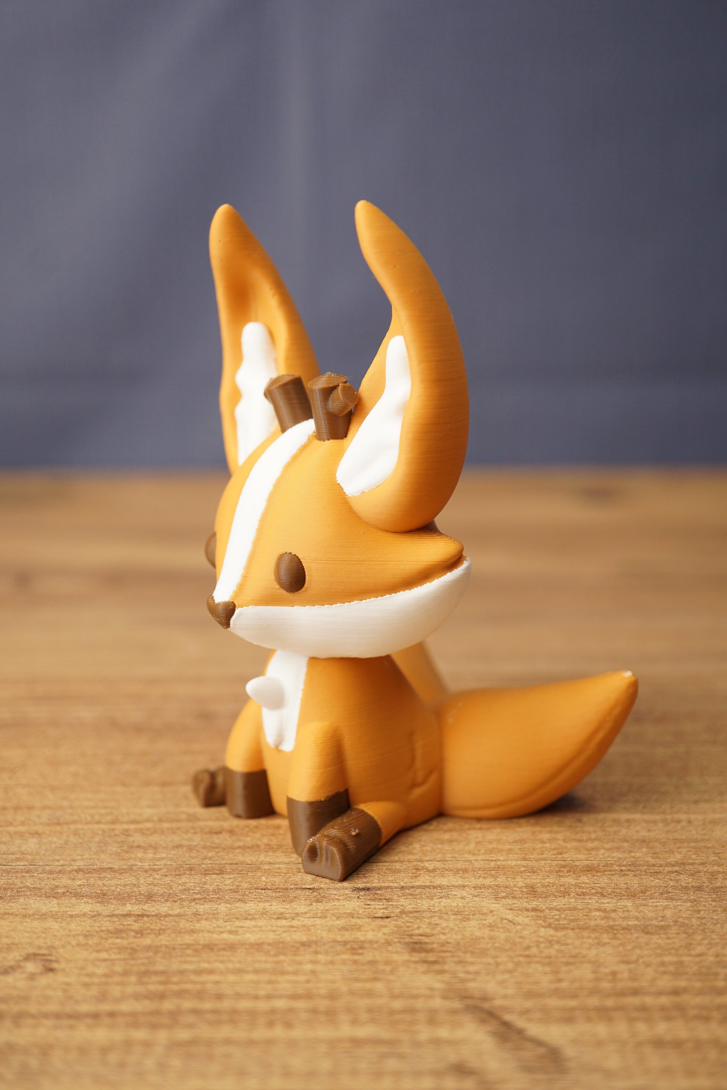 Ancient Kitsuu fox figure side view with orange body, white face and chest markings, brown paws and large sweeping tail