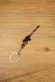 Angled SVDS rifle keychain on wood background with detailed black scope, bronze body and metal keyring for tactical shooter fans