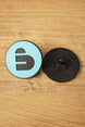 Arc Raiders inspired blue and black pin shown beside the textured black back piece with pin clasp, highlighting front and rear details.