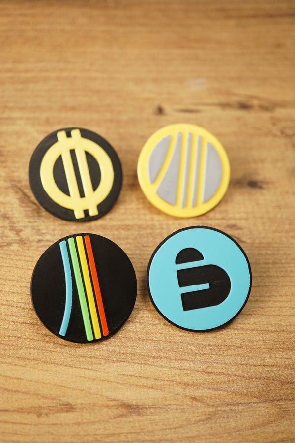 Top-down view of an Arc Raiders inspired pin set with four circular gaming pins arranged on a wood grain surface for a clean product photo.
