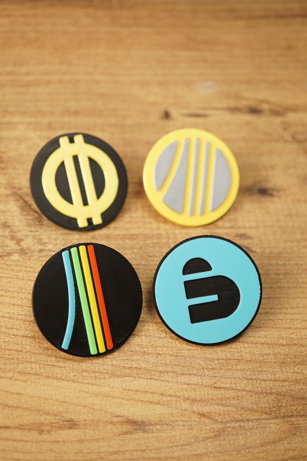 Top-down view of an Arc Raiders inspired pin set with four circular gaming pins arranged on a wood grain surface for a clean product photo.
