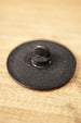 Close-up of the textured black back of an Arc Raiders inspired pin, showing the raised pin clasp and circular accessory design.