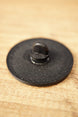 Close-up of the textured black back of an Arc Raiders inspired pin, showing the raised pin clasp and circular accessory design.
