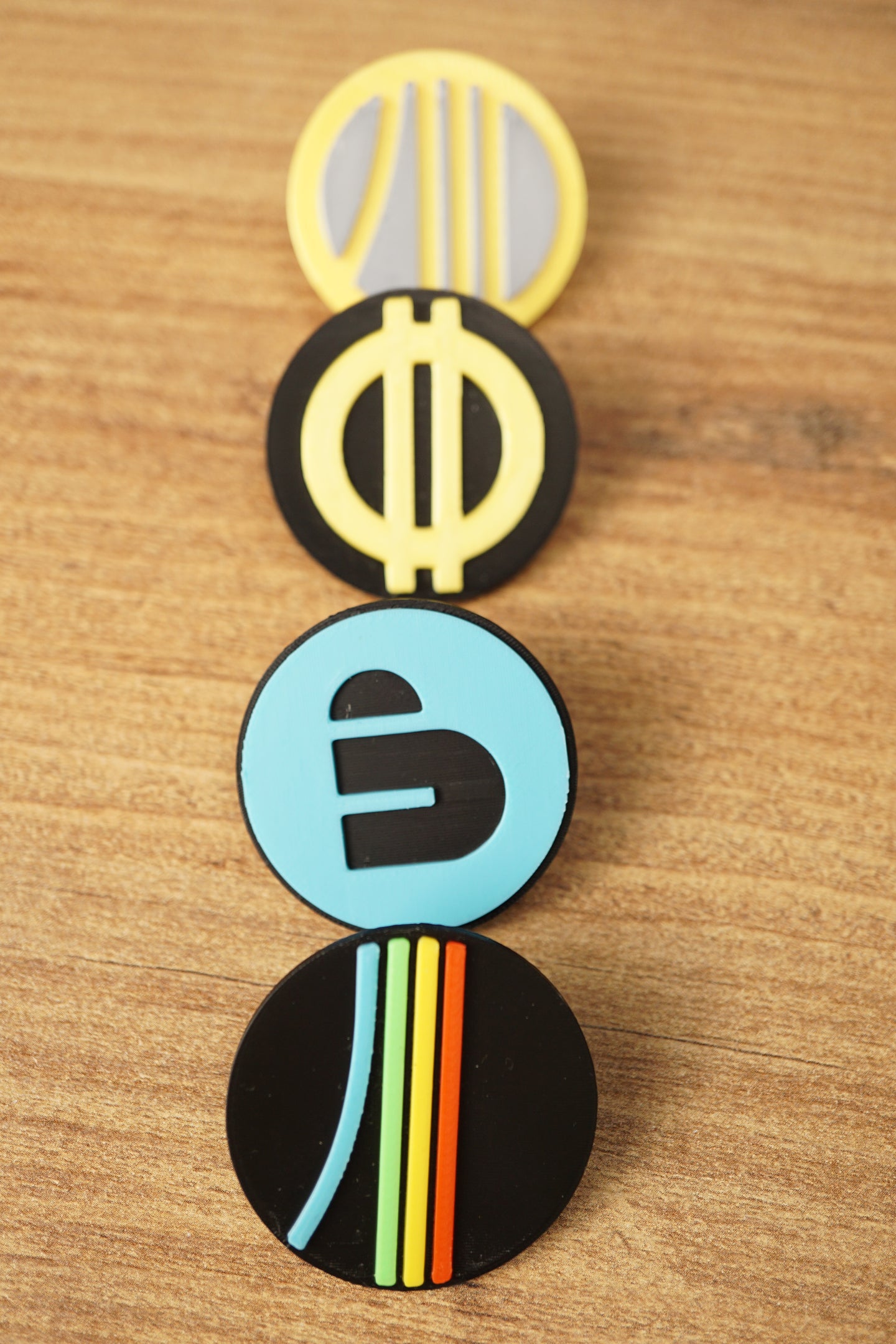 Arc Raiders inspired pin set arranged vertically on a wooden surface, featuring blue, yellow, grey, black, and multicolor round pin designs.