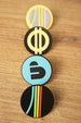 Arc Raiders inspired pin set arranged vertically on a wooden surface, featuring blue, yellow, grey, black, and multicolor round pin designs.
