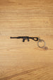 Black AS Val style rifle keychain with long suppressor, compact stock and metal keyring on a wooden tabletop