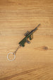 Angled AUG rifle keyring on a wooden background with tactical scope, green stock, metallic barrel and attached silver key ring