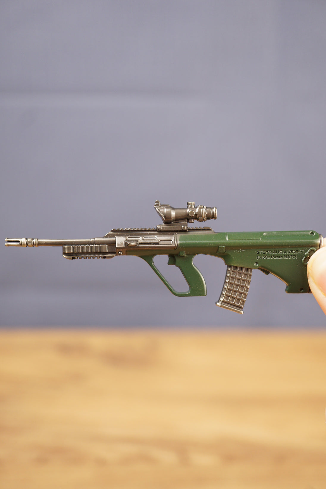 Side view of detailed AUG-style rifle keyring showing green bullpup stock, metal barrel, mounted optic and miniature collectible finish