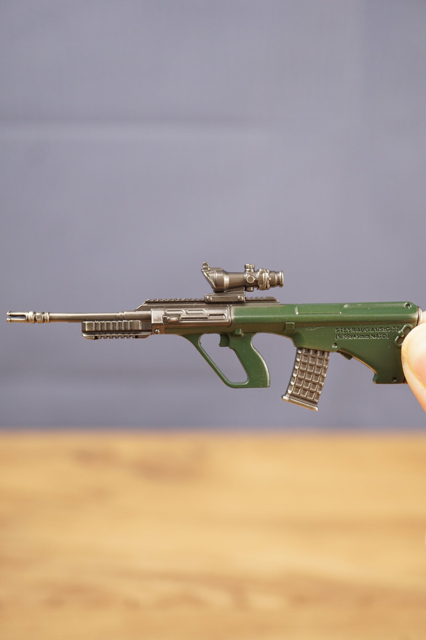 Side view of detailed AUG-style rifle keyring showing green bullpup stock, metal barrel, mounted optic and miniature collectible finish
