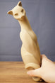 Hand holding a tall beige cat figurine replica, showing the side profile, curved body, 3D printed texture, and detailed sculpted lines.