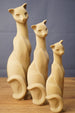 Three stylized beige cat figurine replicas in different sizes, showing curved tails, long necks, and visible 3D printed layer texture.