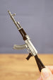 Close-up of black AKM rifle keychain replica held by hand, showing detailed magazine, stock, receiver and barrel styling