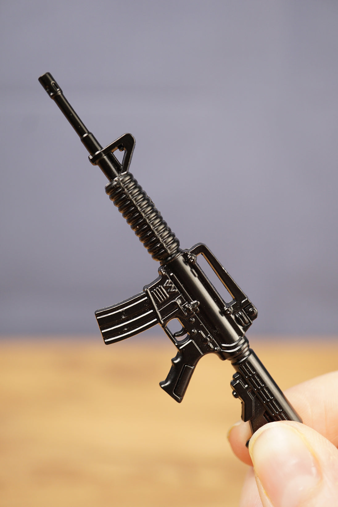 Black miniature rifle keyring held in hand showing classic tactical rifle shape with barrel, magazine and stock detail