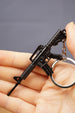 Black tactical rifle keychain close-up with metal key loop, designed as a compact FPS gamer backpack charm.