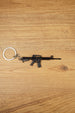 Black tactical rifle keyring with metal chain and key loop on a wooden surface, ideal as an FPS gamer gift.