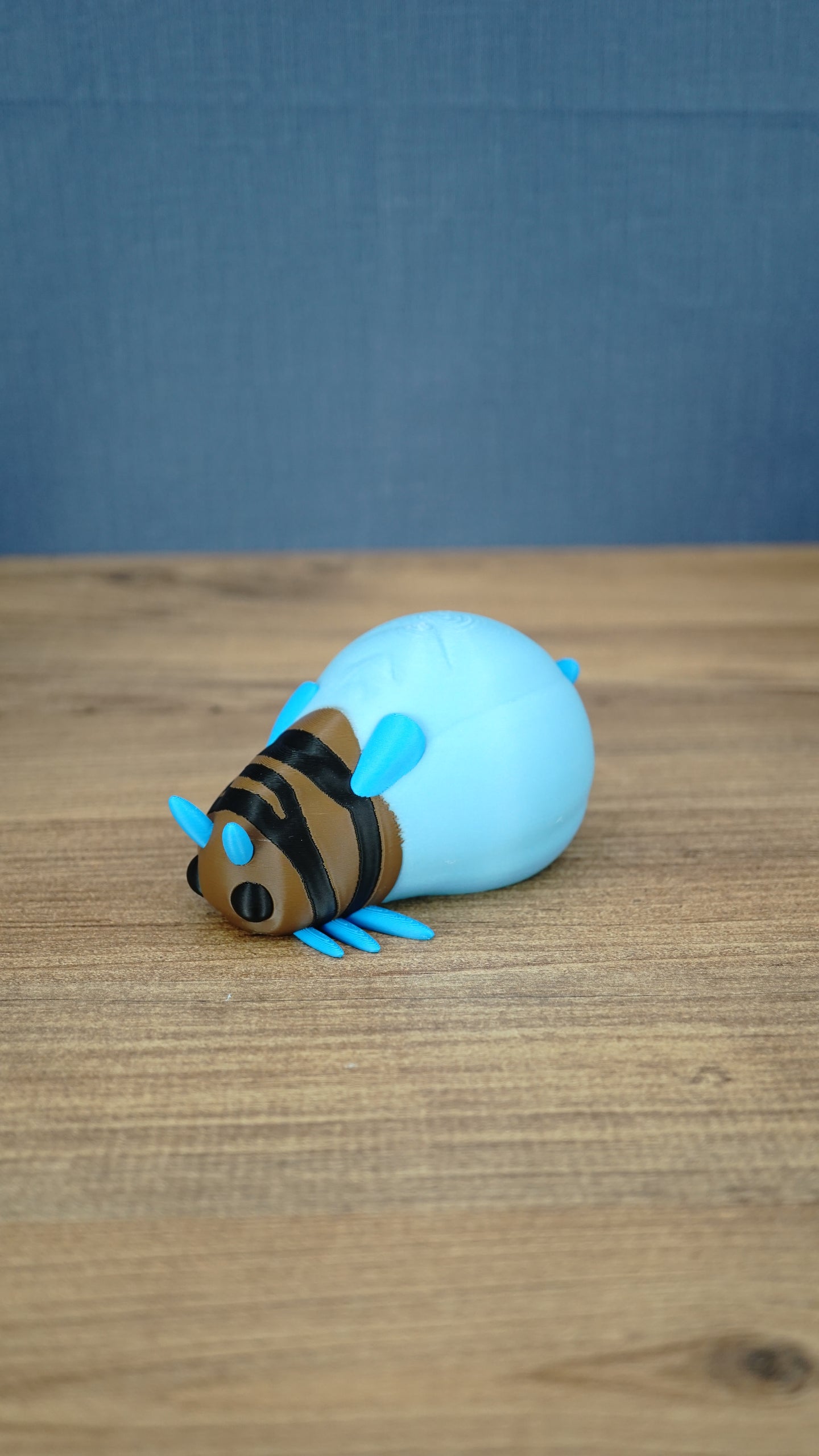 Blue Palia-inspired lantern bug plush figure shown from the front on a wooden tabletop.