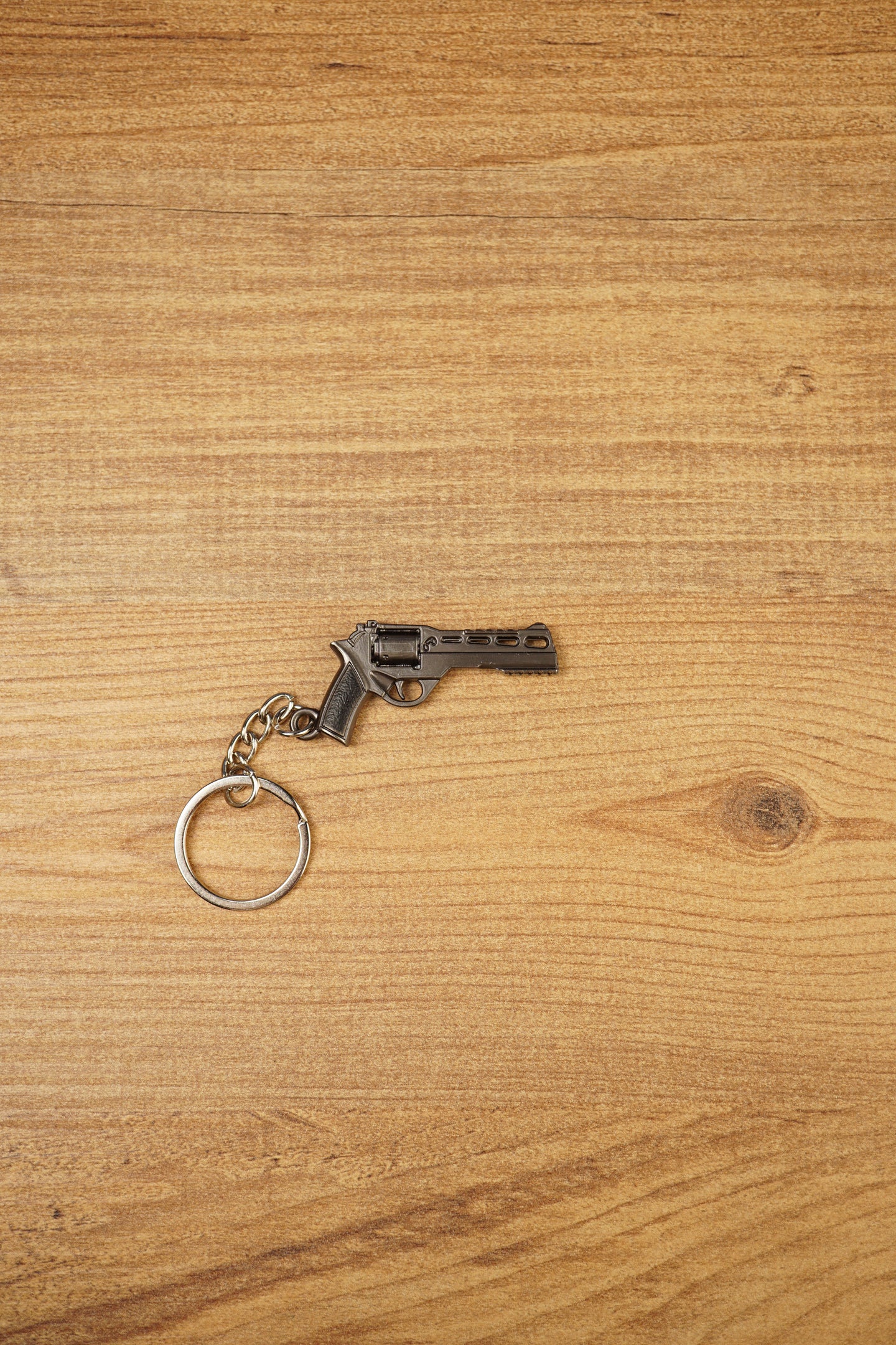 Mini Rhino-style revolver keyring on a wooden surface with gunmetal finish, black grip, and metal chain for FPS gamer gifts