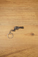 Mini Rhino-style revolver keyring on a wooden surface with gunmetal finish, black grip, and metal chain for FPS gamer gifts