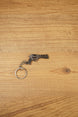 Mini Rhino-style revolver keyring on a wooden surface with gunmetal finish, black grip, and metal chain for FPS gamer gifts