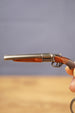 Close-up of miniature double-barrel shotgun keychain showing gunmetal finish, brown grip detail and realistic tactical collectible styling