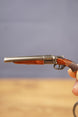 Close-up of miniature double-barrel shotgun keychain showing gunmetal finish, brown grip detail and realistic tactical collectible styling