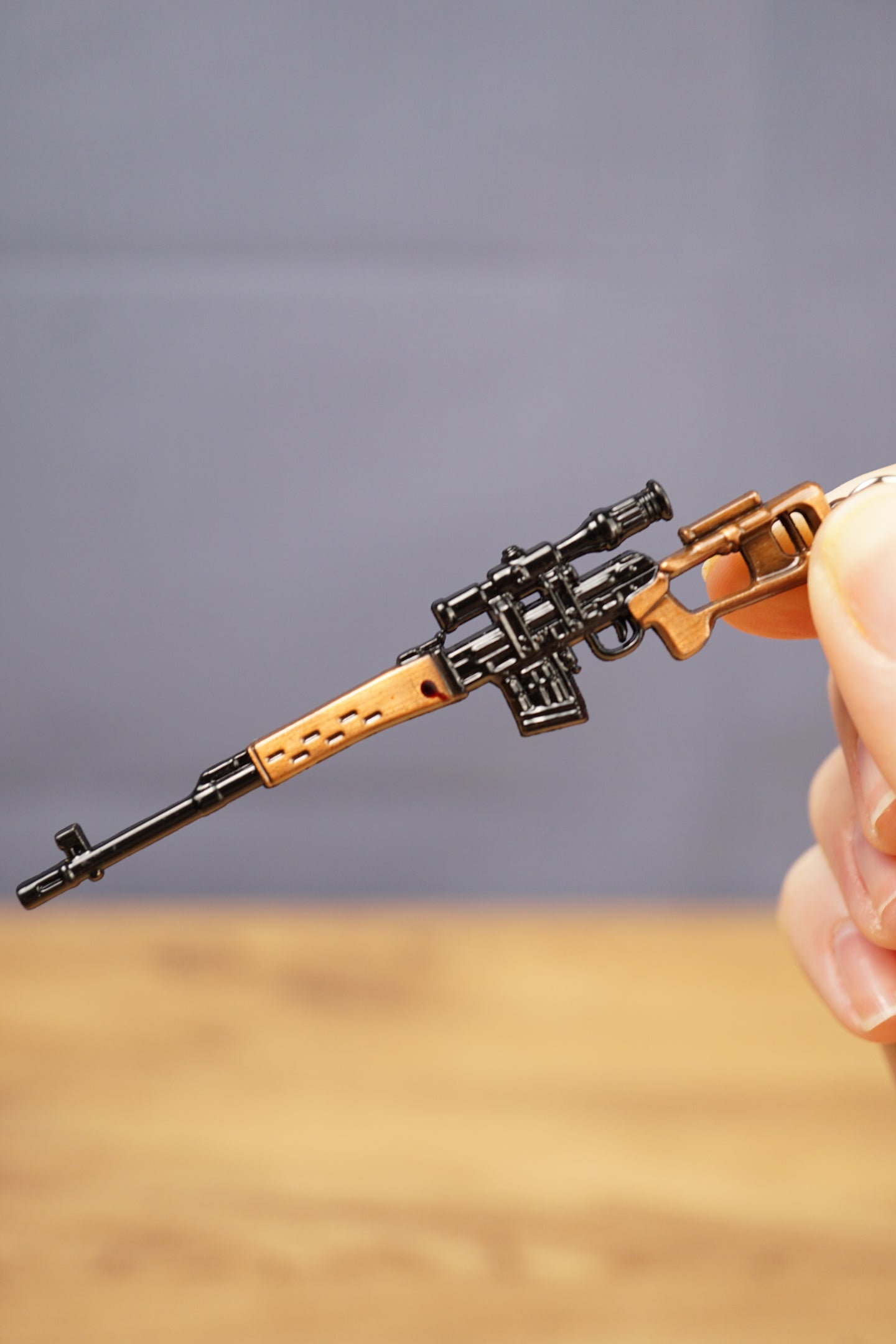 Close-up of SVDS rifle keyring held between fingers, showing the detailed scope, magazine, stock and long barrel design