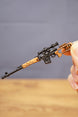 Close-up of SVDS rifle keyring held between fingers, showing the detailed scope, magazine, stock and long barrel design