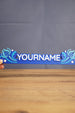 Hand-held blue One-in-Ten-Million style nameplate inspired by Palia, featuring custom white name lettering and fantasy star accents