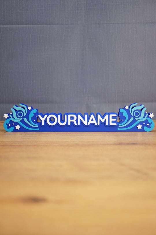 Custom blue Palia-inspired One-in-Ten-Million nameplate with white raised lettering, stars, and decorative swirl details on a wooden desk