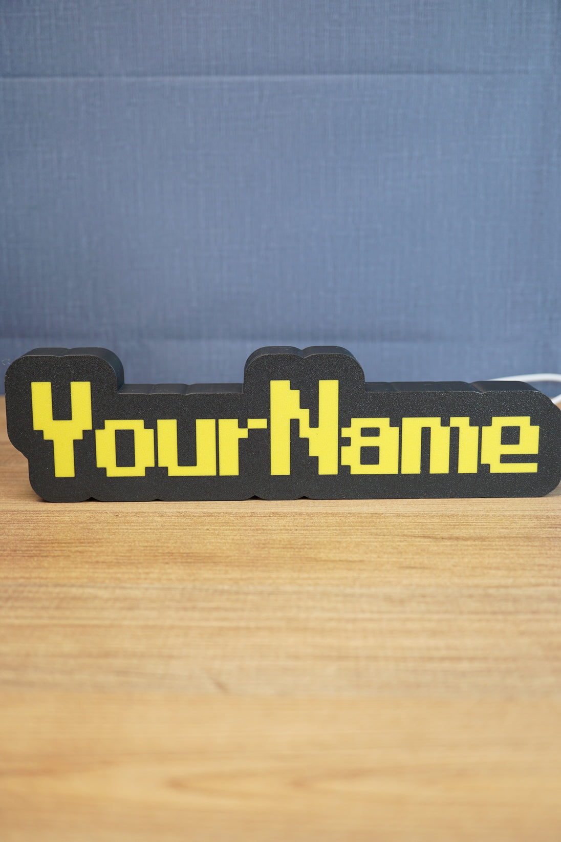Custom YourName LED sign with RuneScape-style font, black casing, and bright yellow lettering on a wooden tabletop.