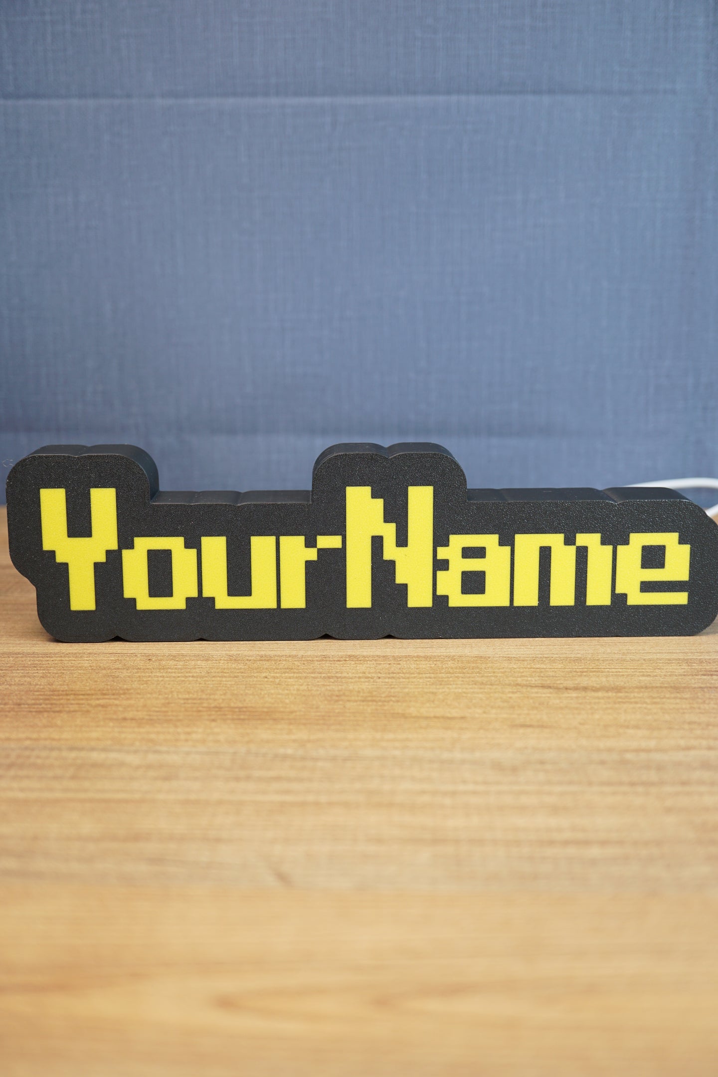 Custom YourName LED sign with RuneScape-style font, black casing, and bright yellow lettering on a wooden tabletop.