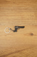 Mini Desert Eagle pistol keychain replica laid flat on a wooden surface, showing the gunmetal finish, black grip and silver split ring attachment