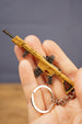 Detailed close-up of tan rifle keychain showing metallic finish, sight, magazine and tactical shooter inspired design.