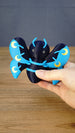 Hand holding the large 12cm Duskwing Butterfly collectible to demonstrate its scale, blue patterned wings and gold crescent details.
