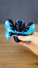 Hand holding the large 12cm Duskwing Butterfly collectible to demonstrate its scale, blue patterned wings and gold crescent details.