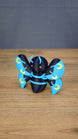 Angled front view of a Duskwing Butterfly plush-inspired collectible showing its rounded body, blue stripes and gold wing markings.