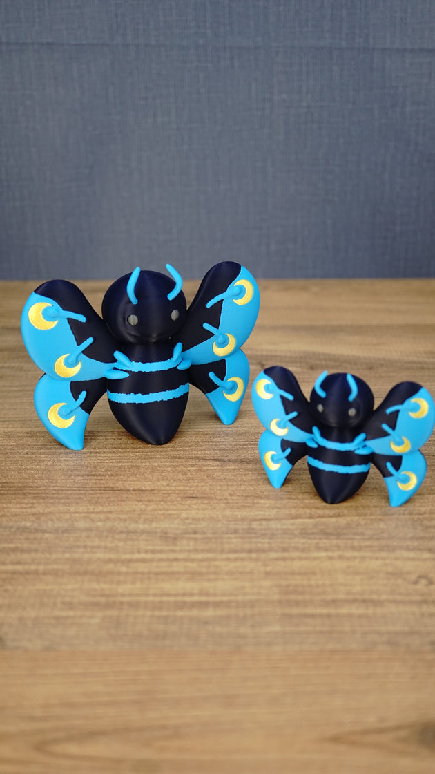 Large and small Duskwing Butterfly plush-inspired figures displayed together, featuring dark-blue bodies, bright-blue wings and gold crescent details.