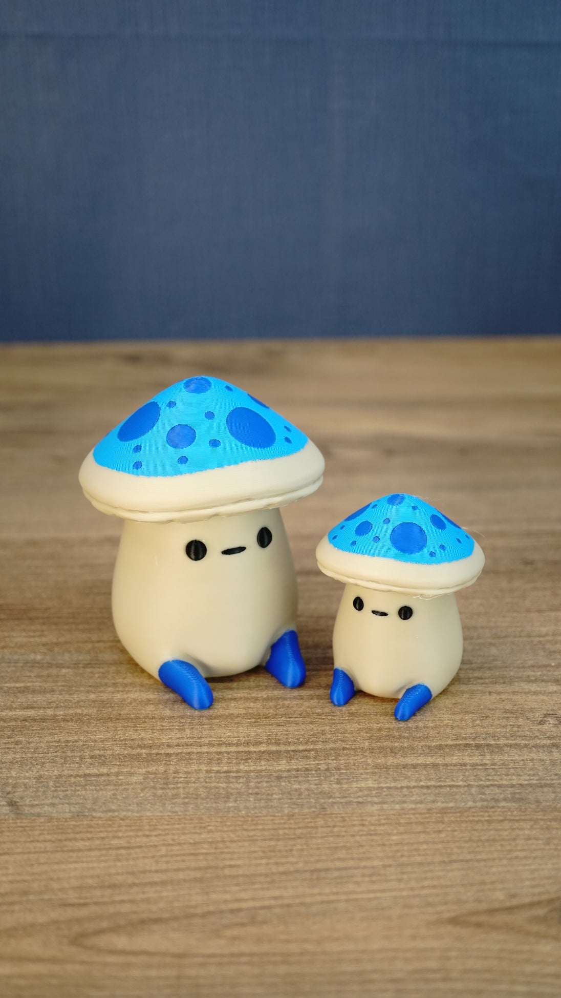 Large and small Elderwood Fun Guy figurines with bright blue mushroom caps, dark blue spots, cream bodies, and blue feet.