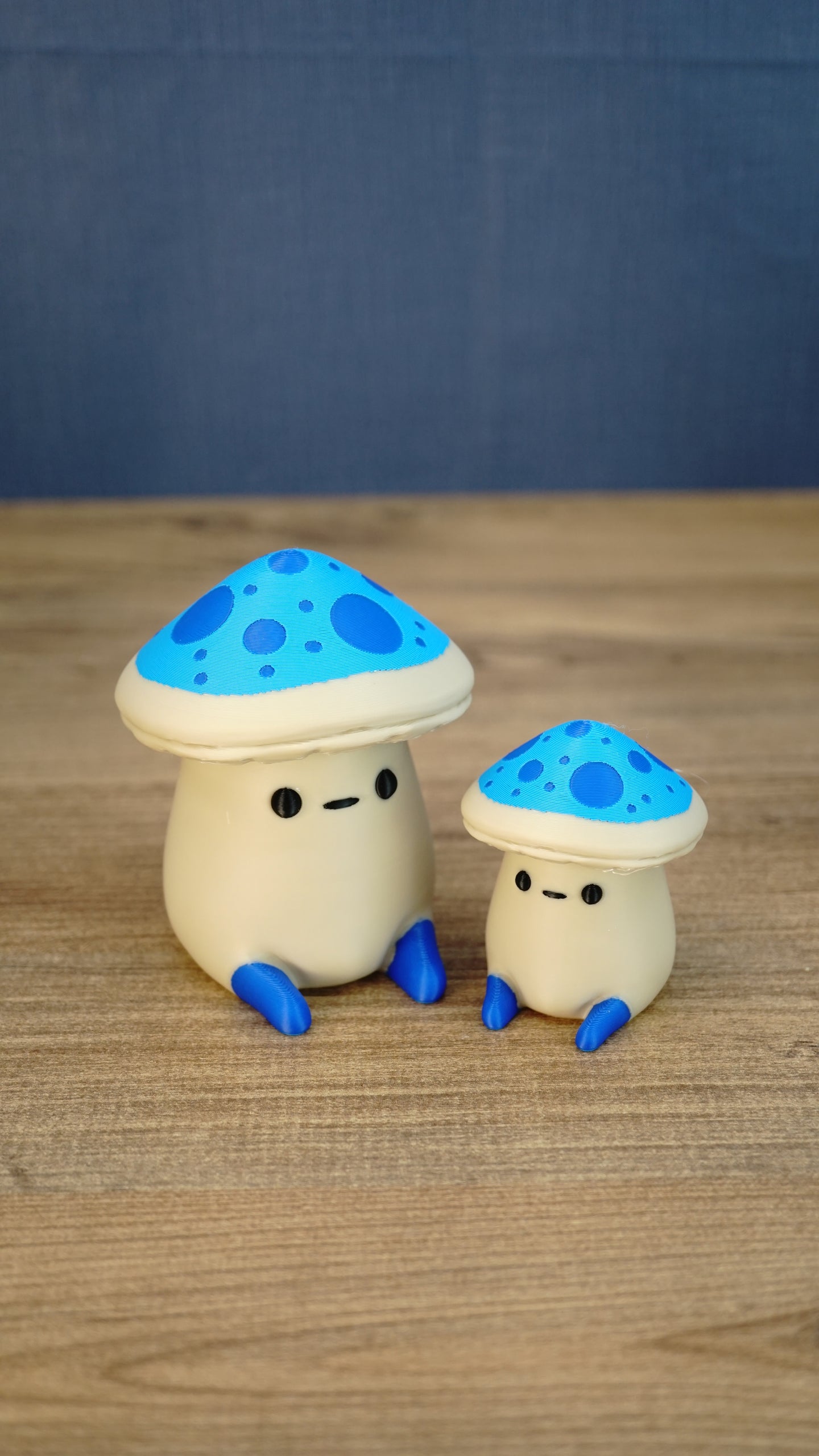 Large and small Elderwood Fun Guy figurines with bright blue mushroom caps, dark blue spots, cream bodies, and blue feet.