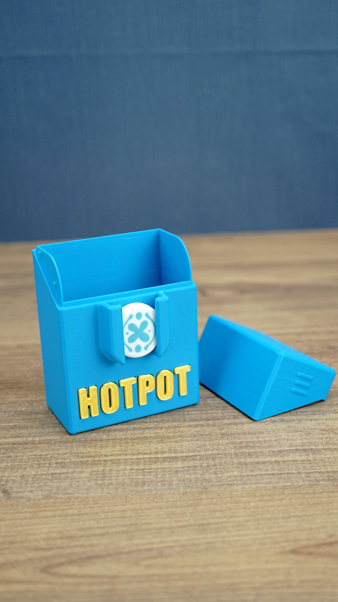 Empty blue Palia Hotpot storage box with gold Hotpot lettering and white pass token detail, shown open with its lid beside it.