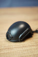 Black FAST MT helmet bottle opener keychain inspired by Tarkov, shown from the side with rail details, front mount, and keyring on a wooden desk.